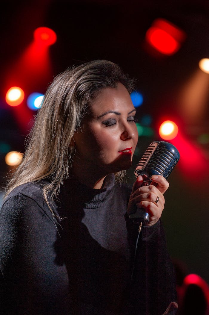 A female singer passionately singing into a vintage microphone on a vibrant stage.
